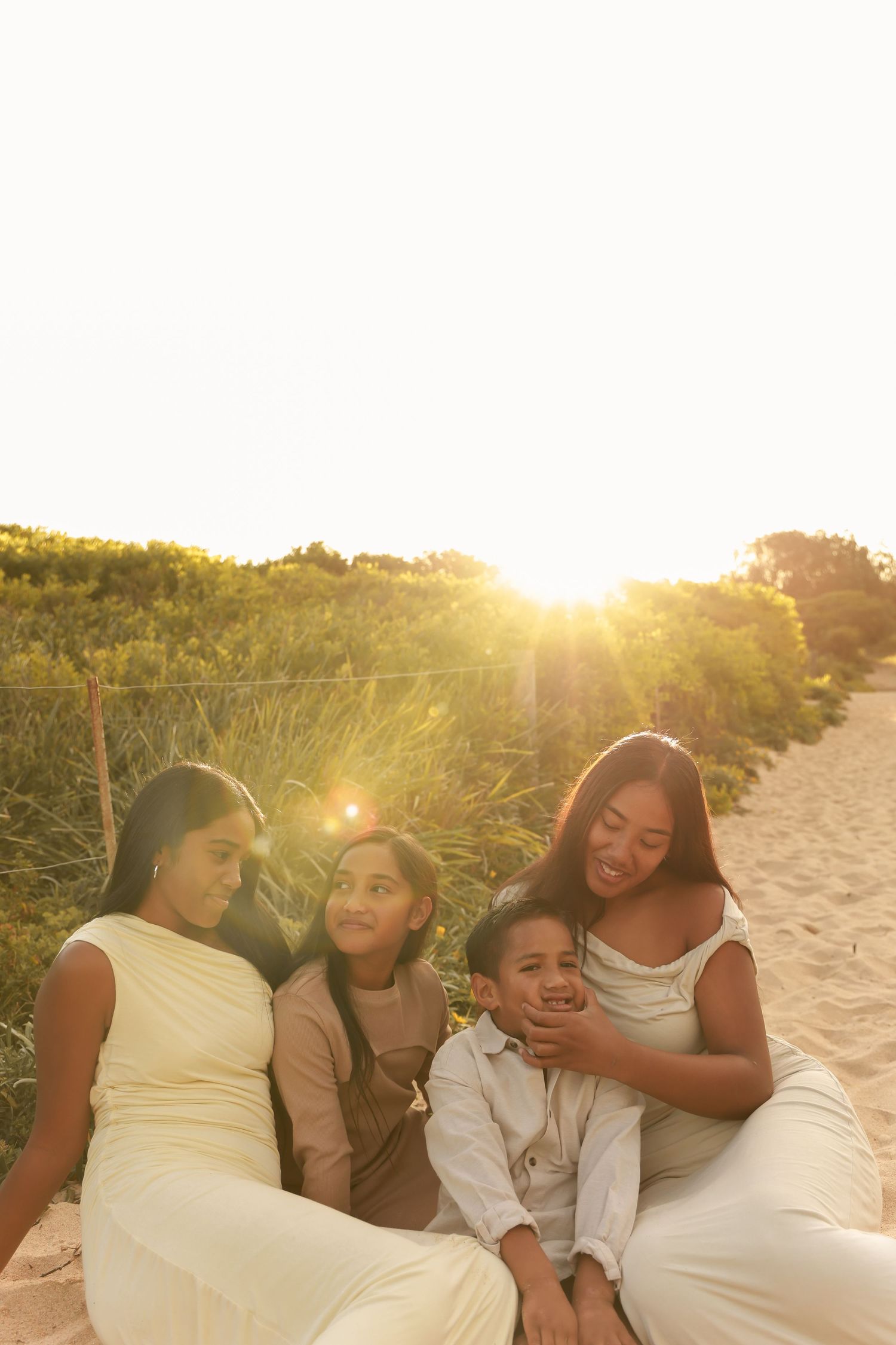 A group relaxes together on a sandy beach at sunset with warm golden light illuminating the scene.