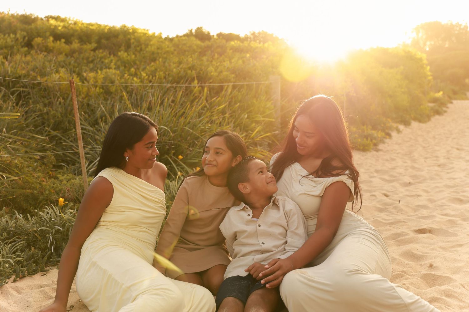 A family enjoys a tender moment together on a sandy beach at sunset, creating a warm and intimate silhouette.