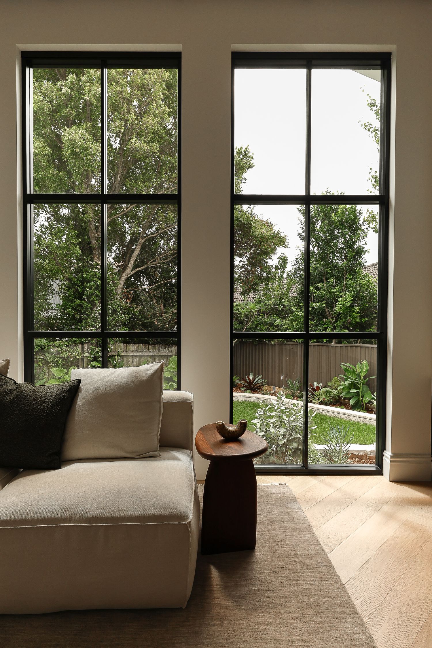 Contemporary living space with floor-to-ceiling windows, hardwood floors, and modern lounge furniture.