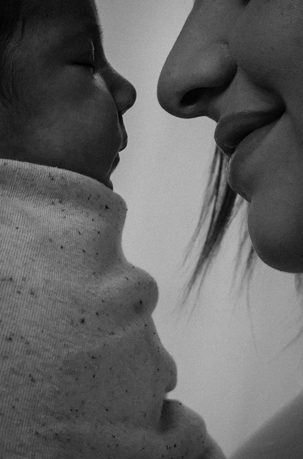 Close-up silhouettes of faces about to kiss in dramatic black and white.