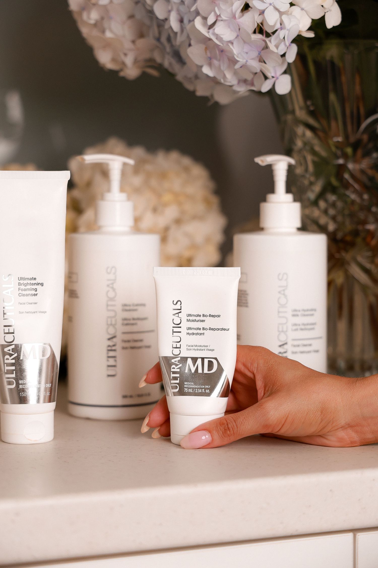 Collection of white skincare product bottles lined up on white surface.