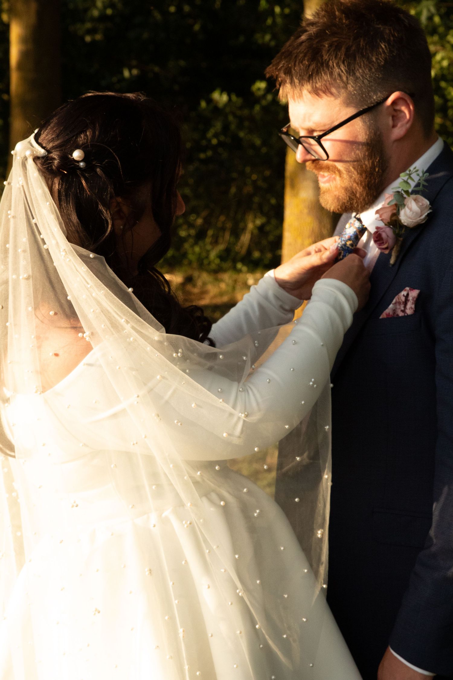Sunlit wedding portraits with flowing veil creating ethereal atmosphere.