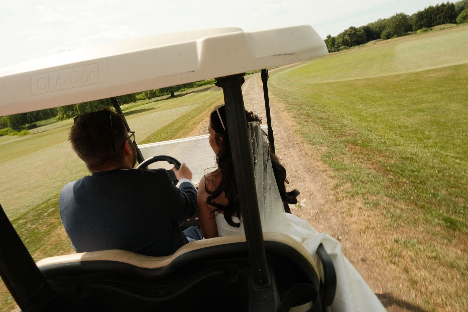 Golf cart path winding through a sunny green course on a summer day.