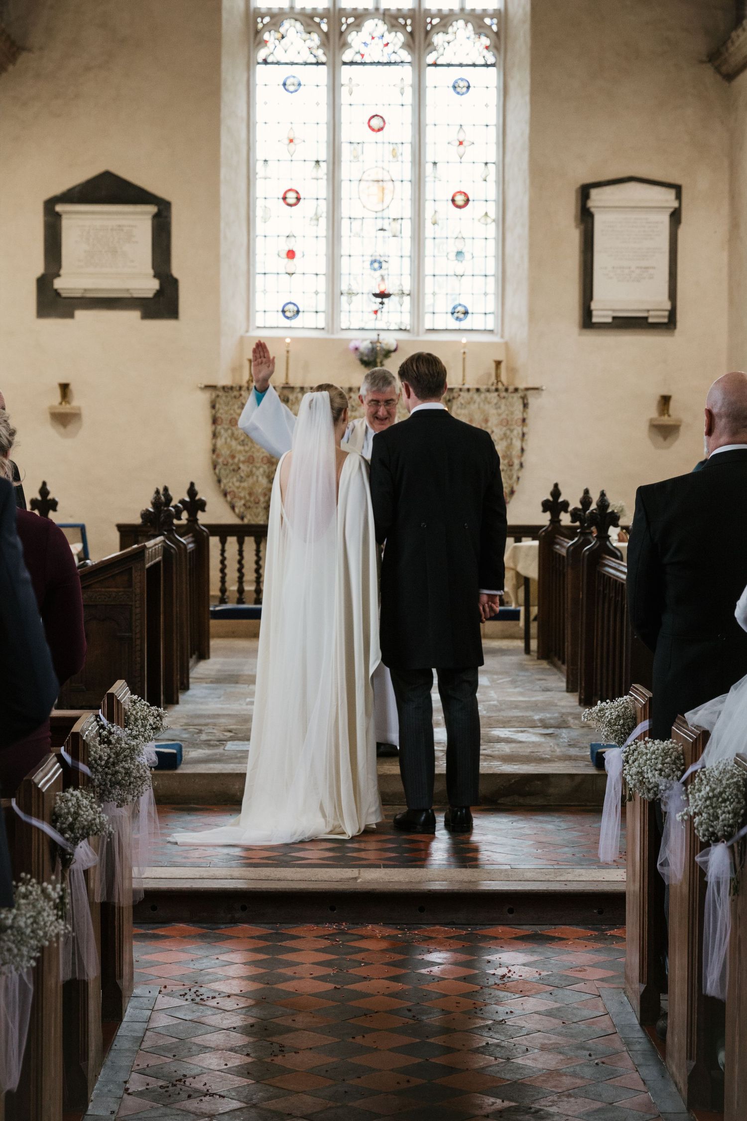 Traditional church wedding ceremony with stained glass windows and decorated pews.