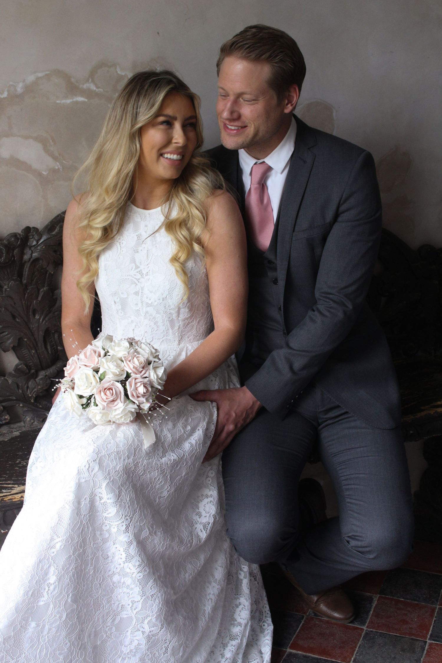 A couple in wedding attire share an intimate moment while seated together indoors.