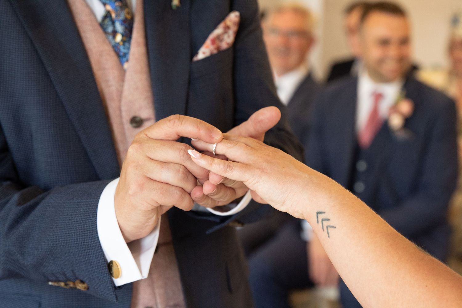 Close-up of hands during a wedding ring exchange ceremony.