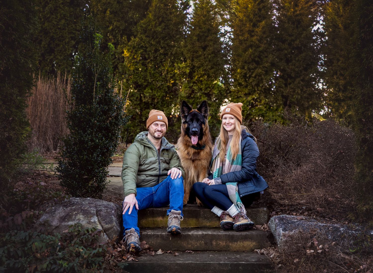 Couple sits beside German Shepard dog during pet photography session at Knoxville Botanical Gardens