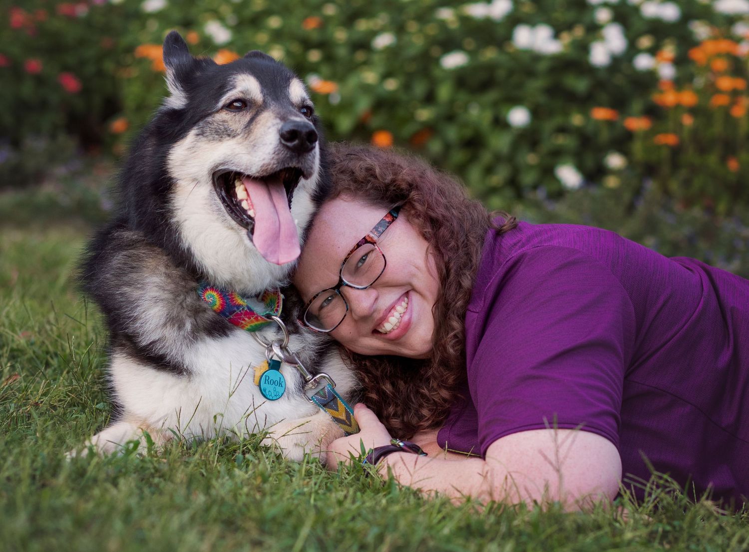 Woman lays in grass smiling as she cuddles her dog during pet photography session at UT Botanical Gardens in Knoxville TN