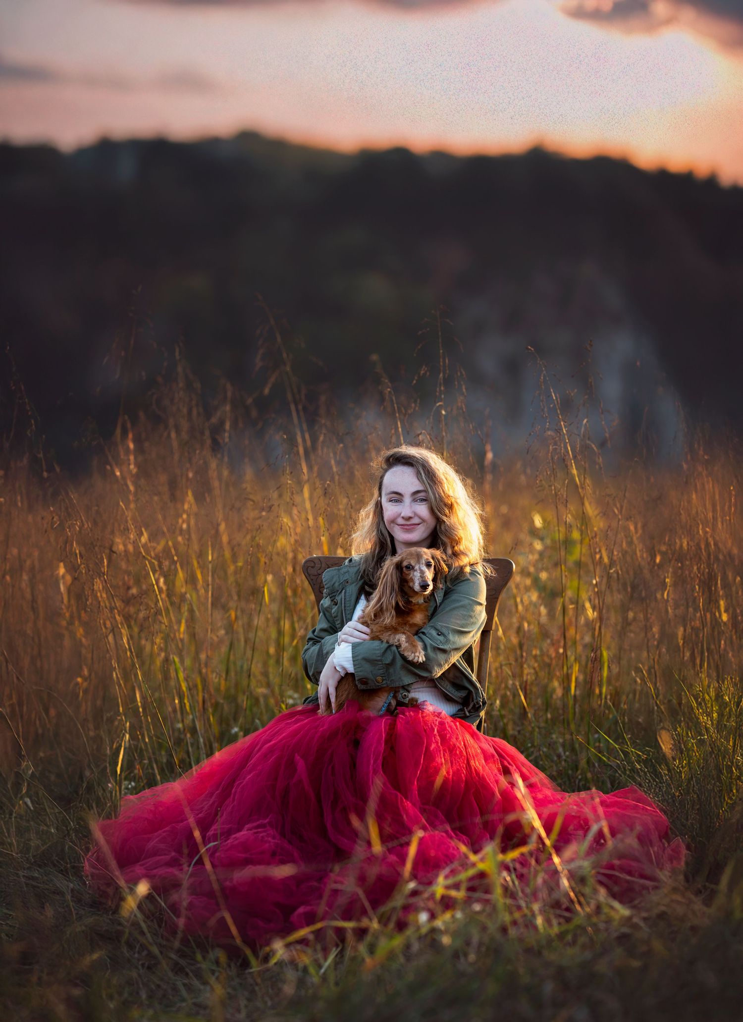 Woman in red tulle skirt sits in chair holding her dog at sunset for a pet photography session in Knoxville TN at Melton Hill Park