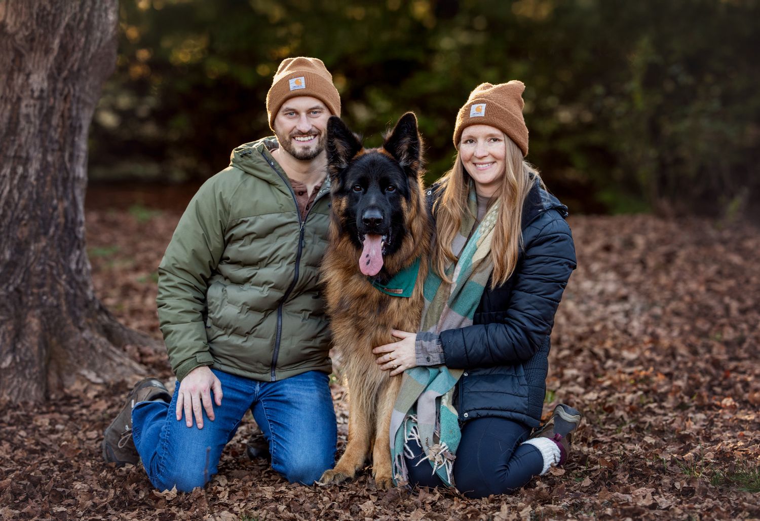 Couple kneels beside German Shepard in winter hats at Knoxville Botanical Gardens in Knoxville TN