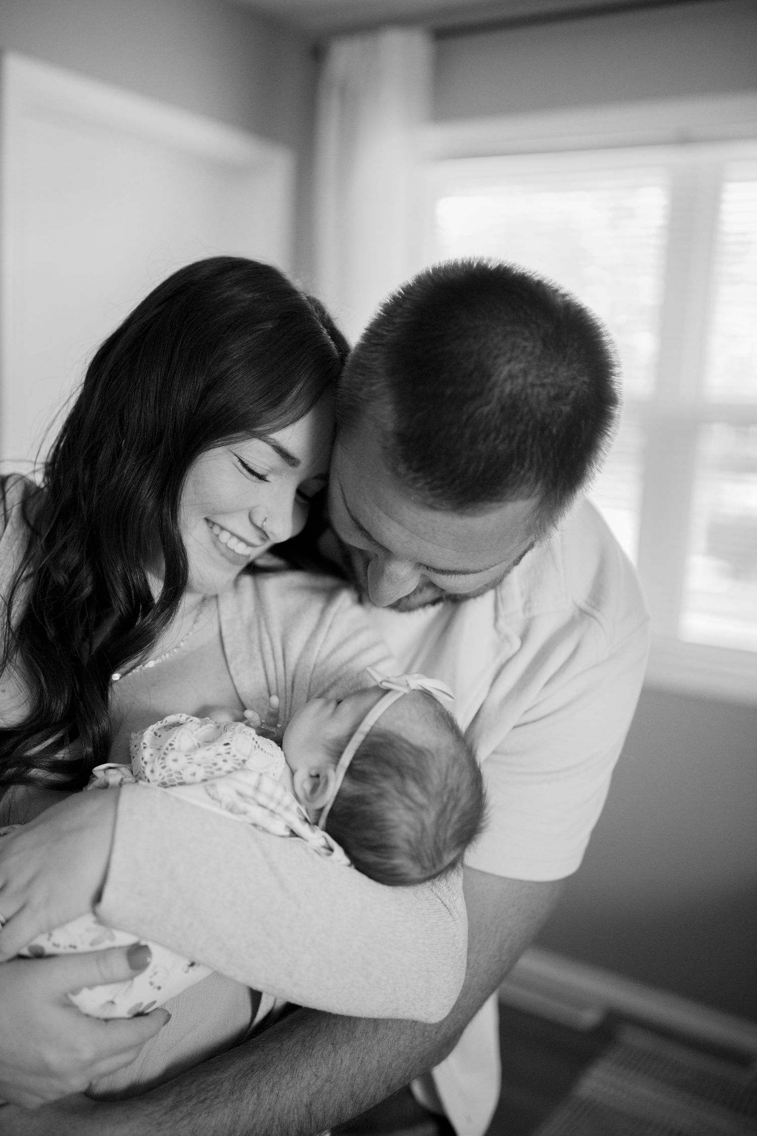 Lifestyle newborn photography of parents holding their baby at home, photographed by Jessica Rose Photography, Evansville WI.