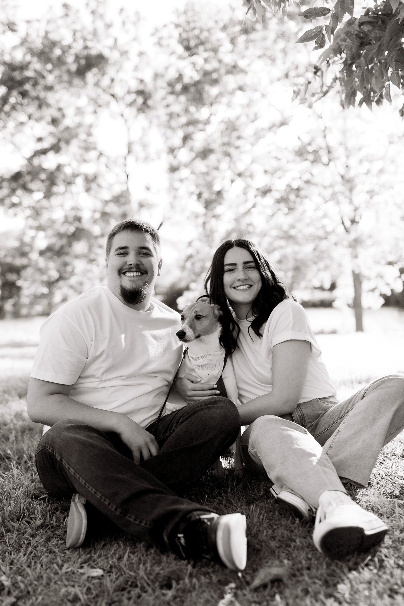 Couple laughing with their dog during an engagement photo session, captured by Jessica Rose Photography in Janesville, Wisconsin.