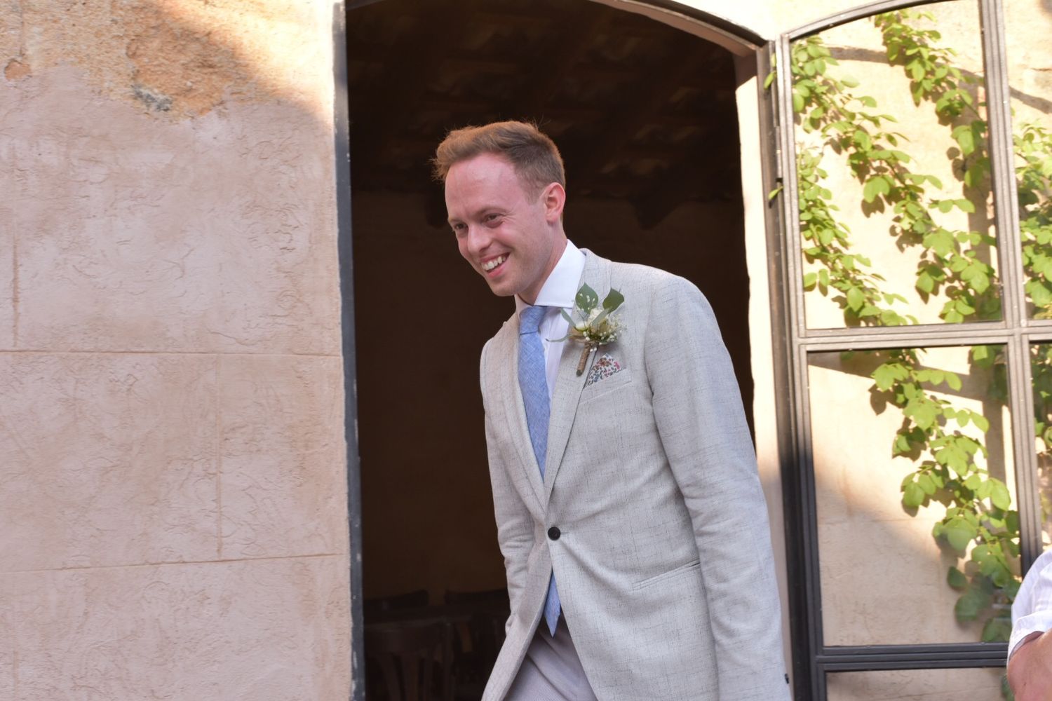 Wedding celebration candid moments outside a rustic stone venue in natural daylight.