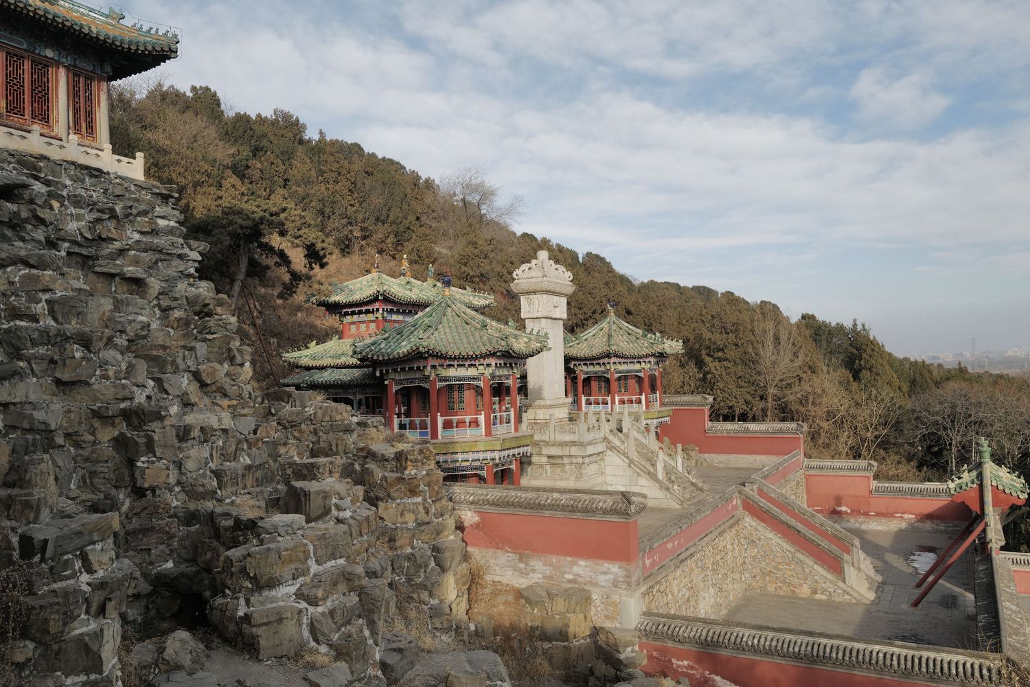 Traditional Chinese temple buildings nestled on a hillside with stone walls and ornate architecture.