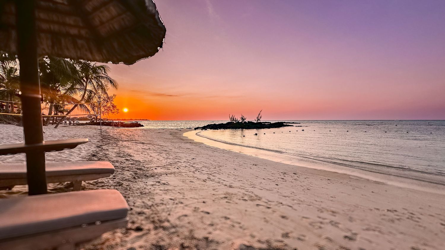 Dramatic purple and orange sunset over a pristine coastal beach.