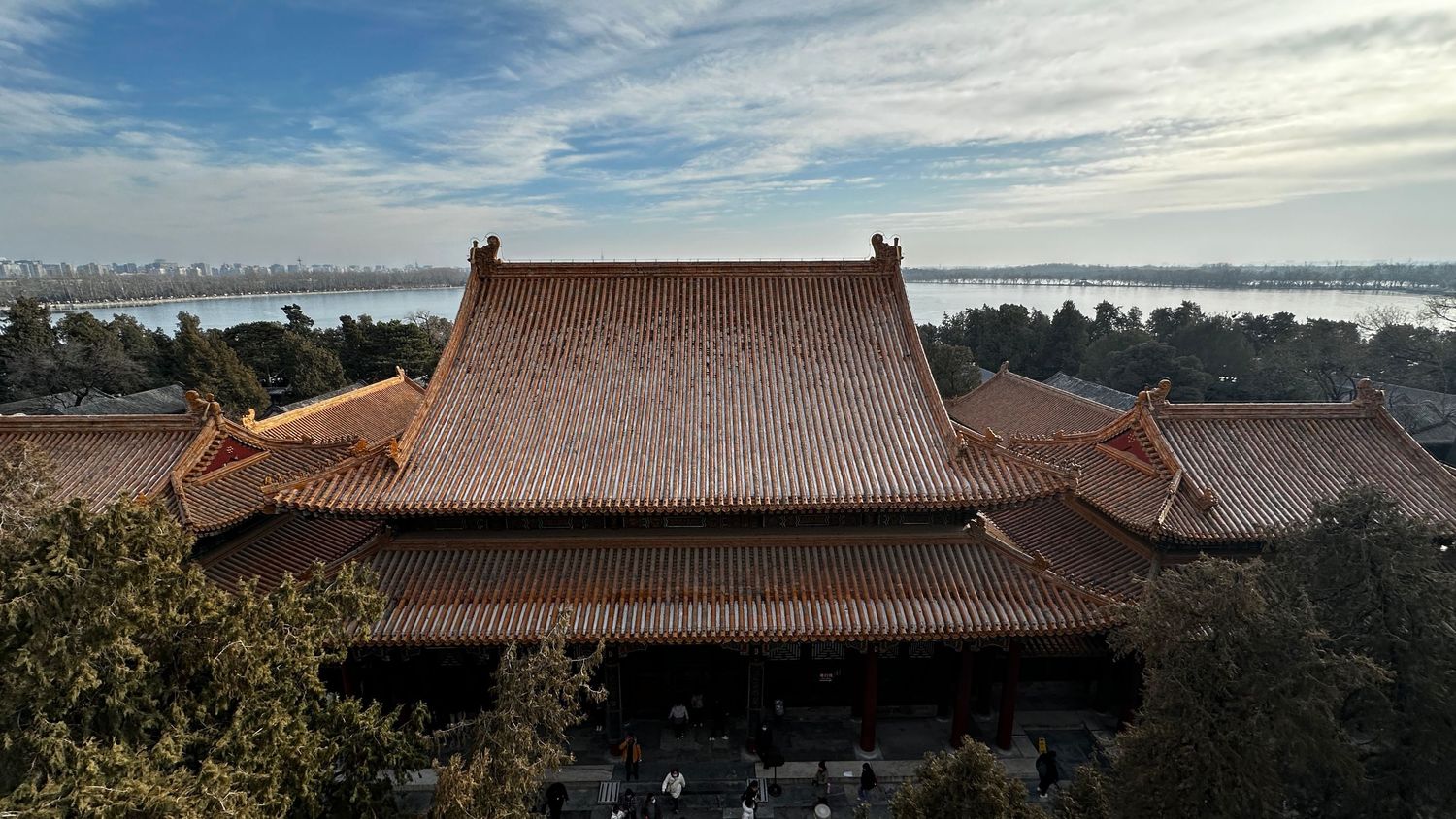 Traditional Chinese temple with tiled roof overlooking a scenic waterfront on a sunny day.