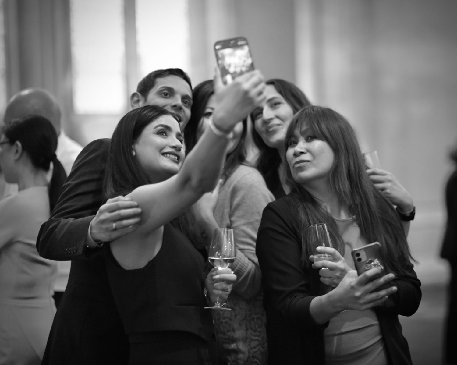 Black and white candid photography of people socializing at an indoor event.