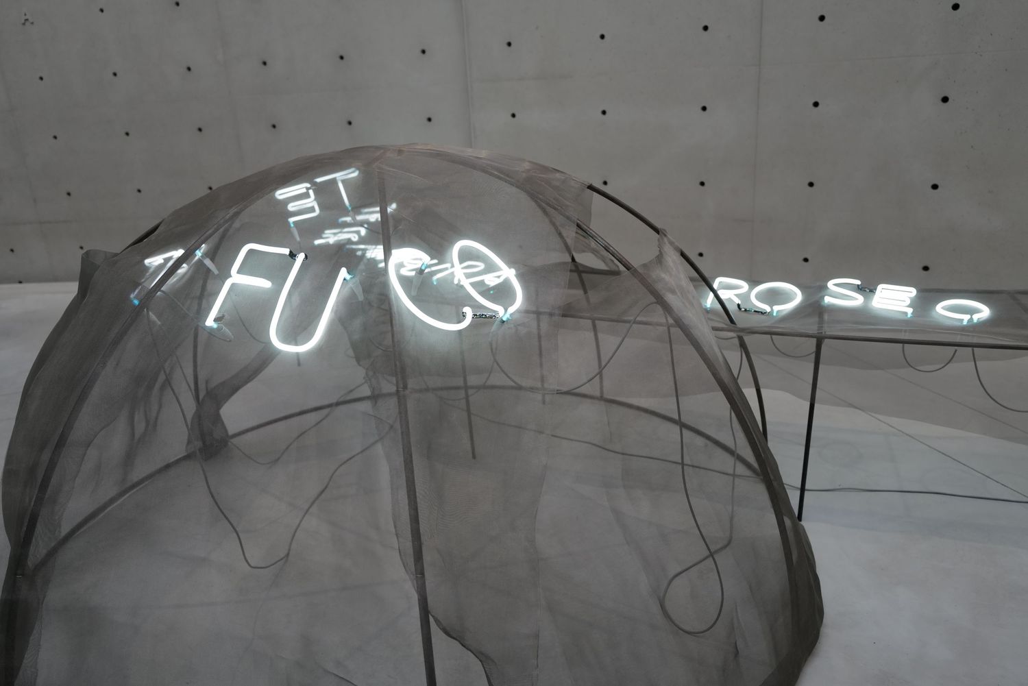 Contemporary art installation with glowing neon numbers projected on concrete walls.