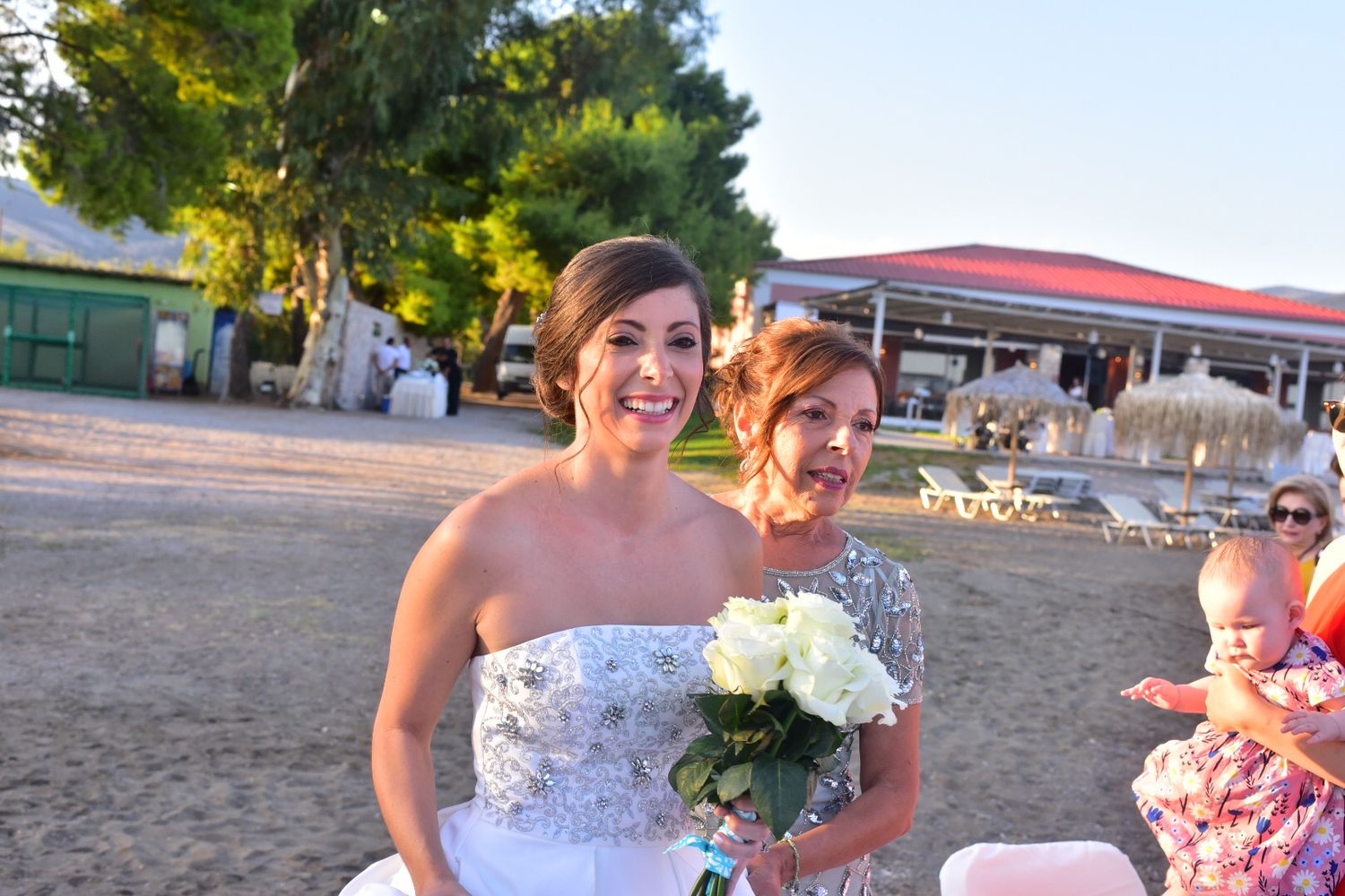Wedding celebration scene at sunset with white floral bouquets.