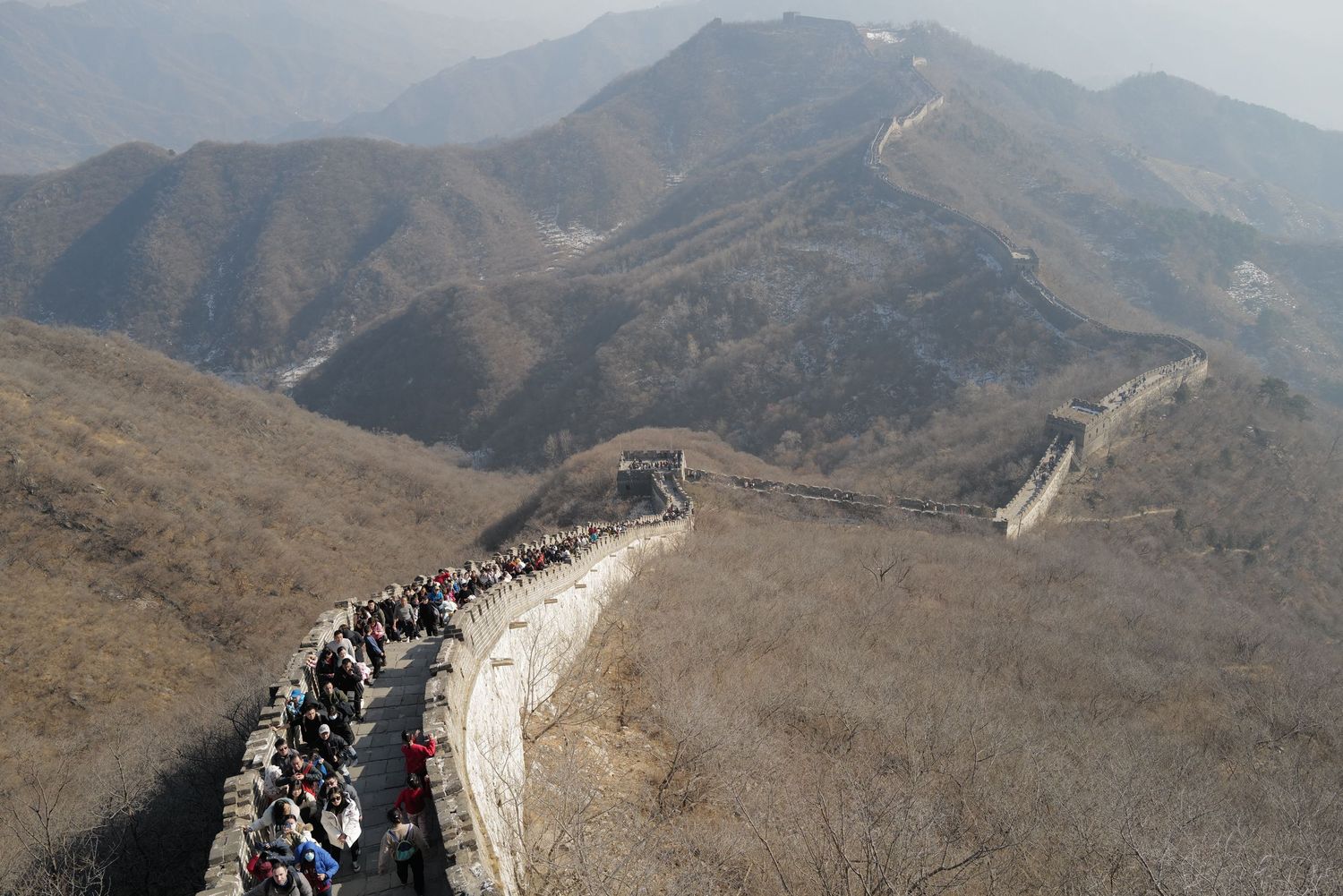 Crowded section of the Great Wall of China winding through mountainous terrain.