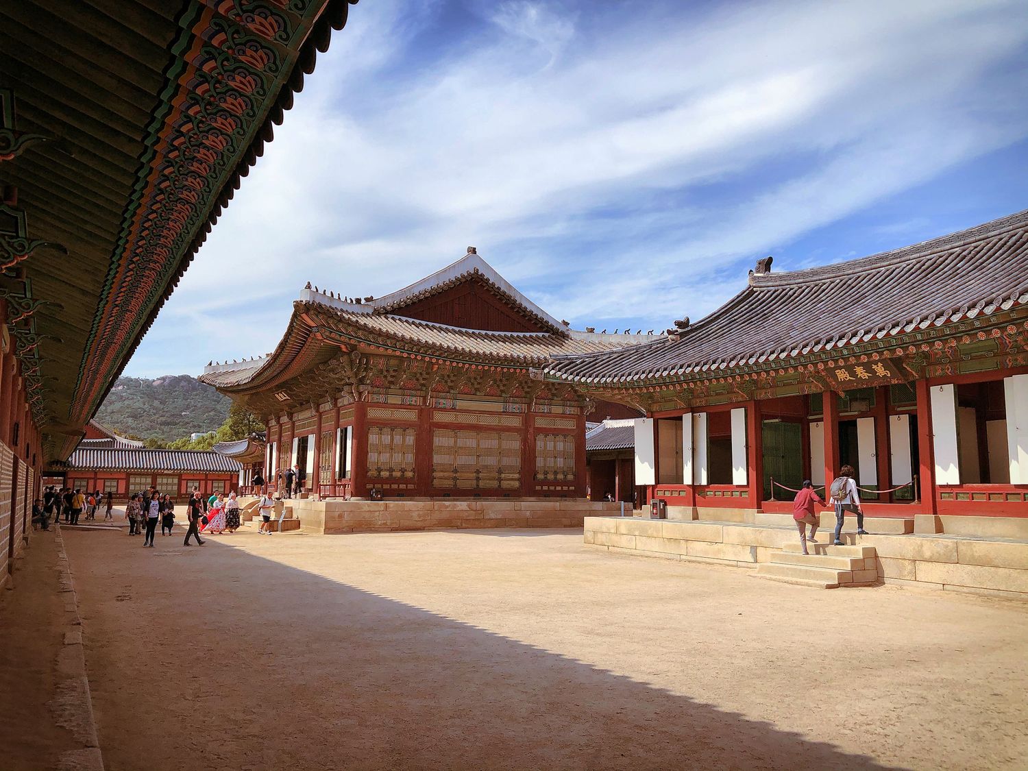 Traditional Korean palace courtyard with wooden buildings and blue sky in Seoul.