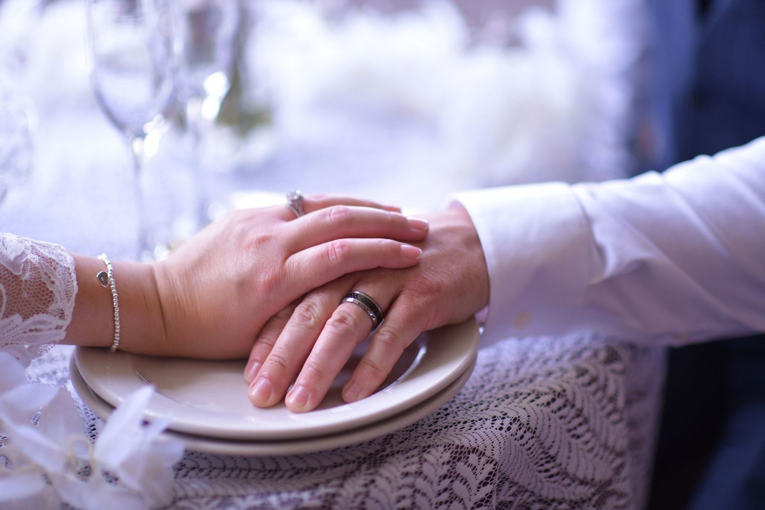 Silver place setting with white porcelain plates and linens on a formal dining table arranged for an elegant meal.