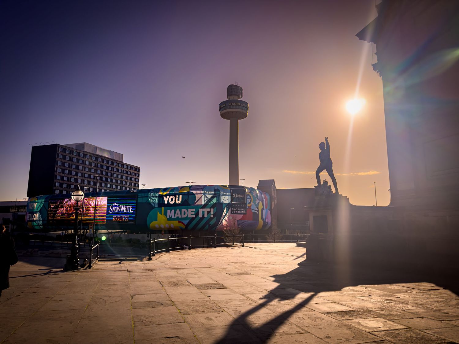 Misty urban landscape at sunset with silhouettes of buildings and structures creating a moody atmosphere.
