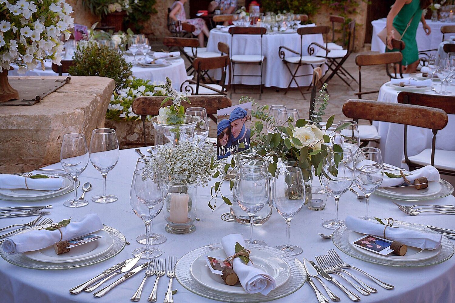 Elegant wedding reception table settings with white floral centerpieces and crystal glassware.