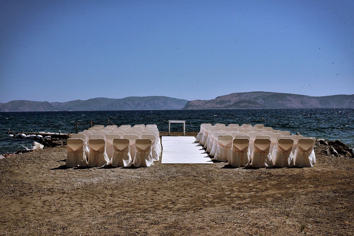 White chairs arranged in rows for an outdoor wedding ceremony overlooking a scenic mountain lake.