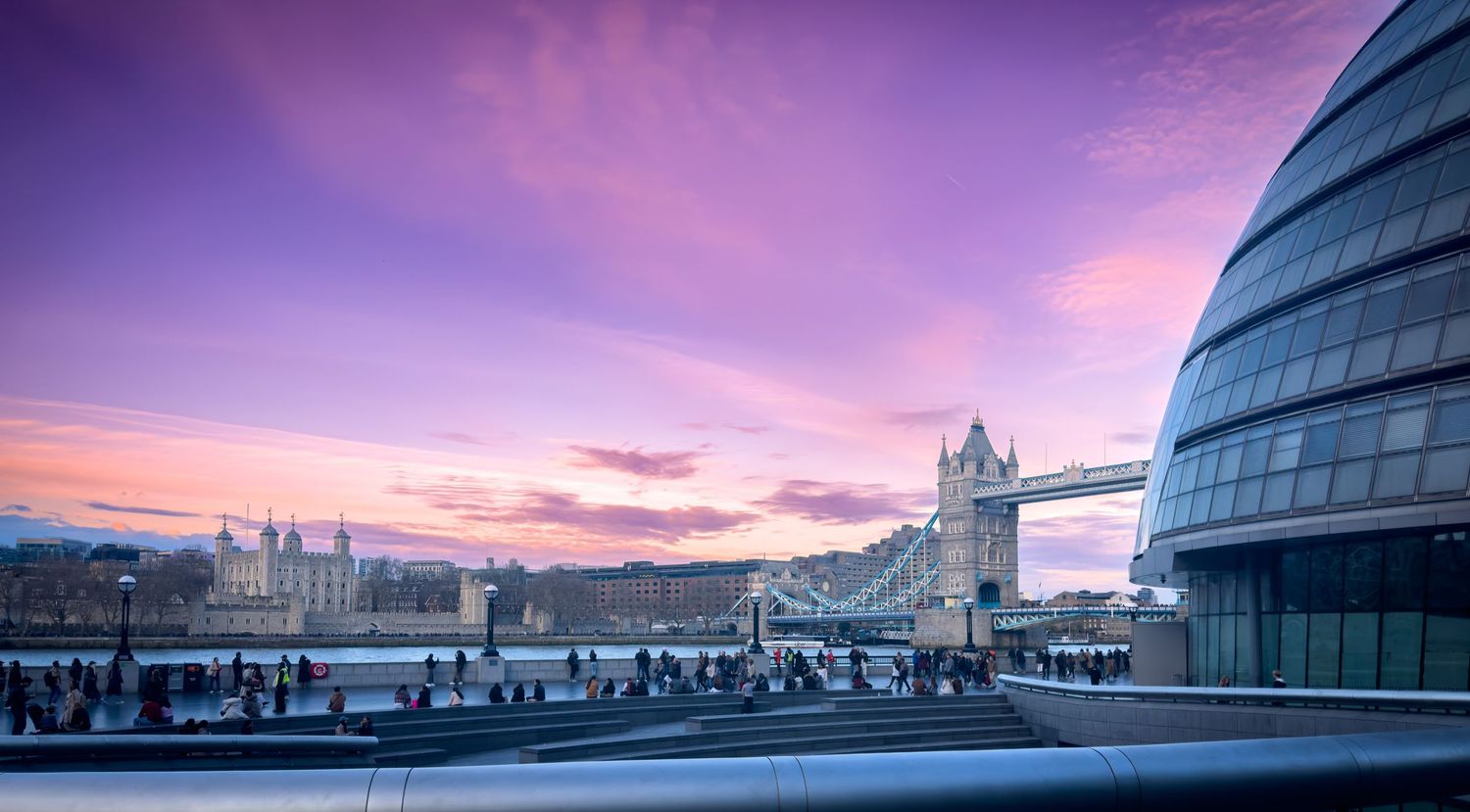 Purple and pink sunset sky over modern city buildings creating a panoramic urban vista.