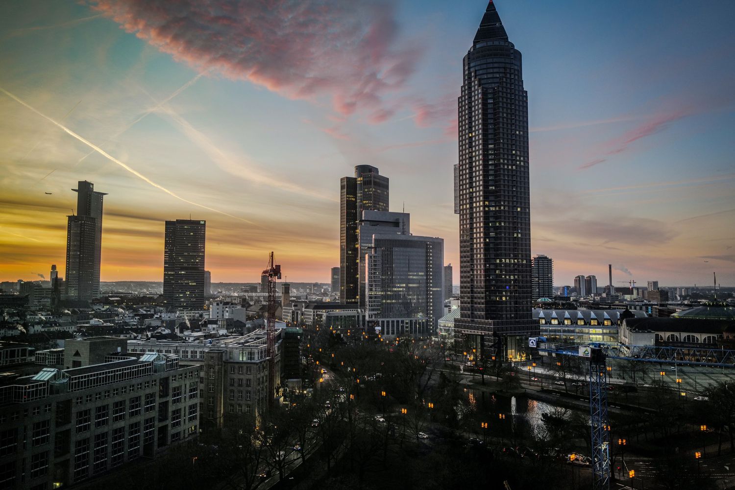 Frankfurt skyline silhouetted against dramatic sunset sky with Messeturm tower prominent.