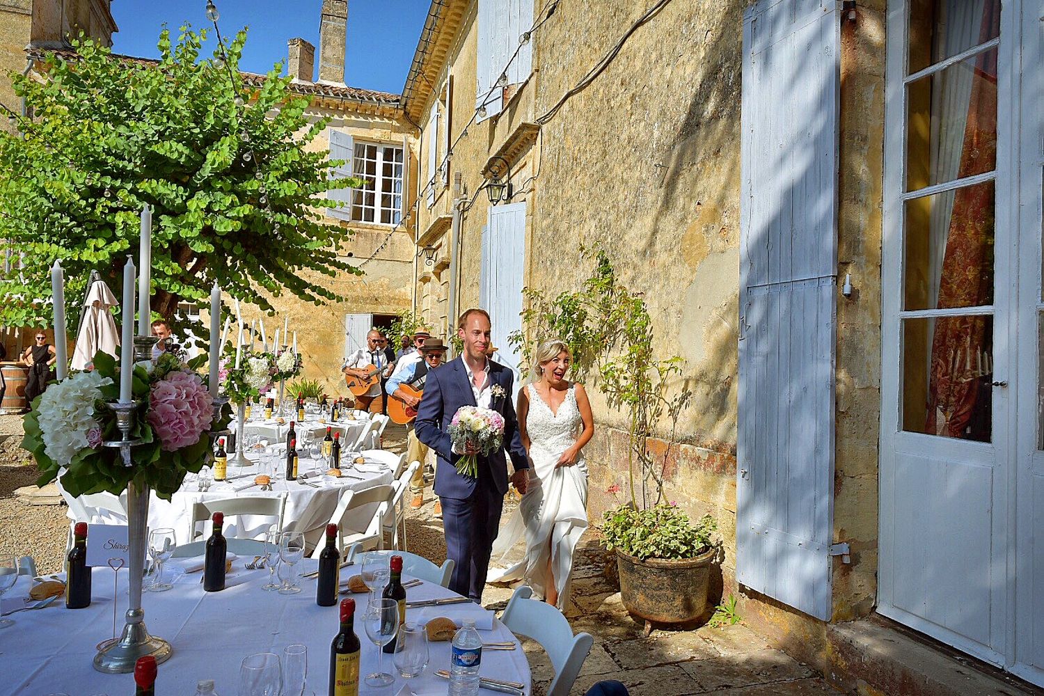Outdoor dining setup at a charming French countryside restaurant with tables arranged in front of a stone building.