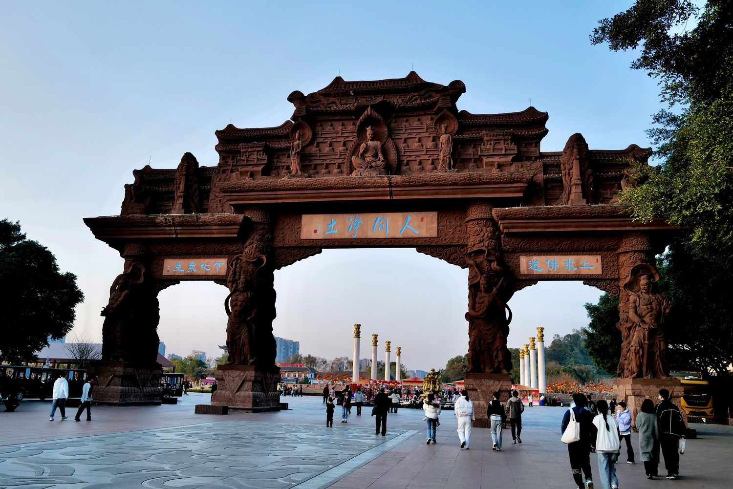 Ornate stone archway entrance with traditional Chinese architectural details and visitors walking beneath.