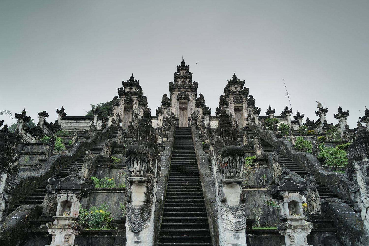 Ancient Balinese temple with dramatic stone staircase and ornate gates leading upward.