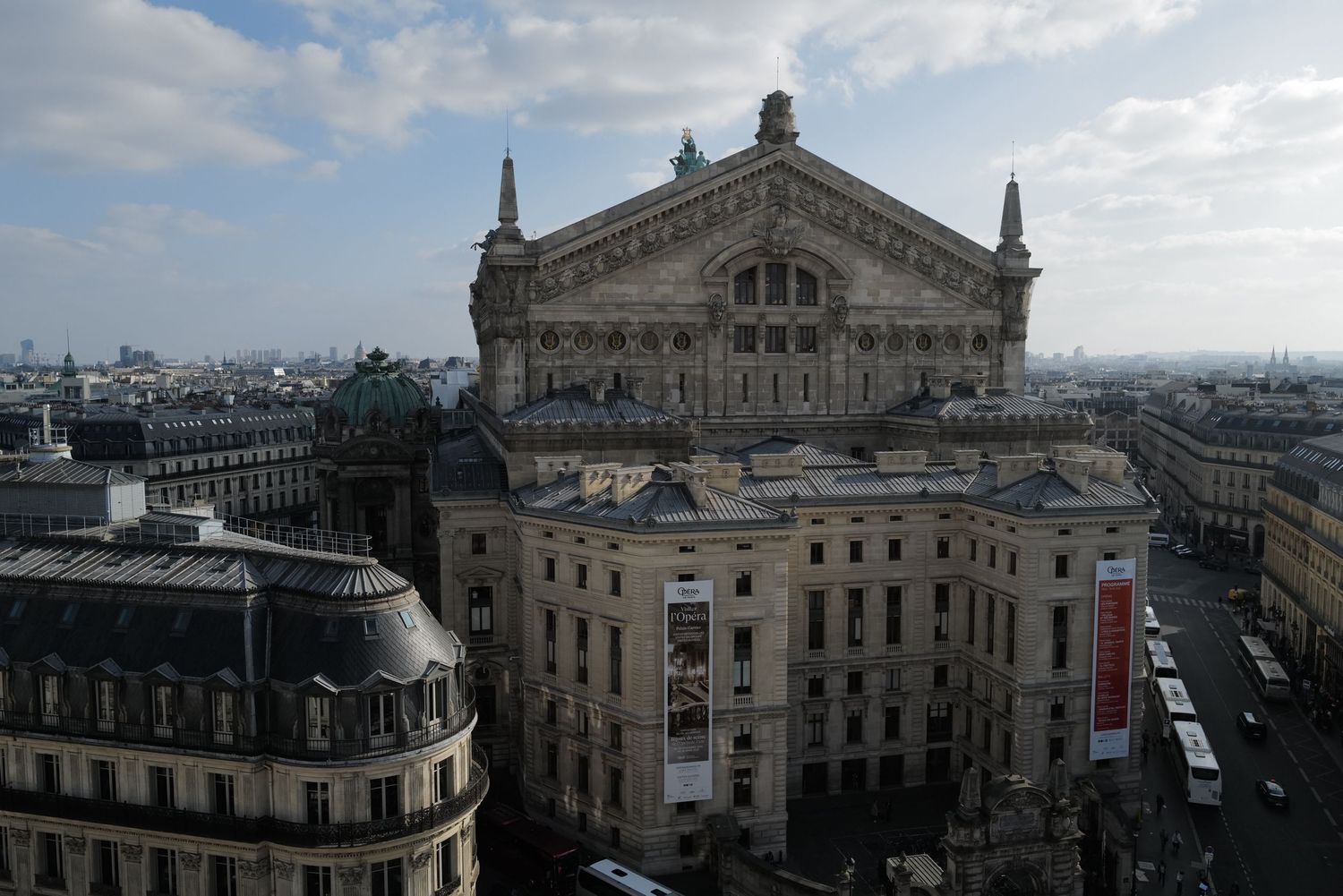 Panoramic view of Paris Opera House and surrounding buildings under cloudy sky.