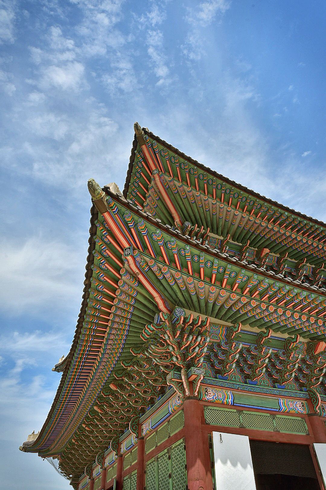 Ornate traditional Korean temple roof architecture with detailed paintwork against blue sky.
