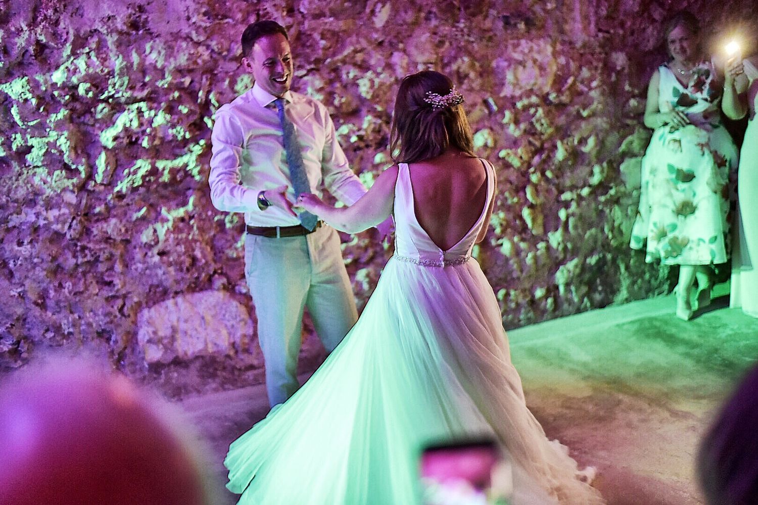 Wedding reception dance floor bathed in vibrant purple and green lighting effects.