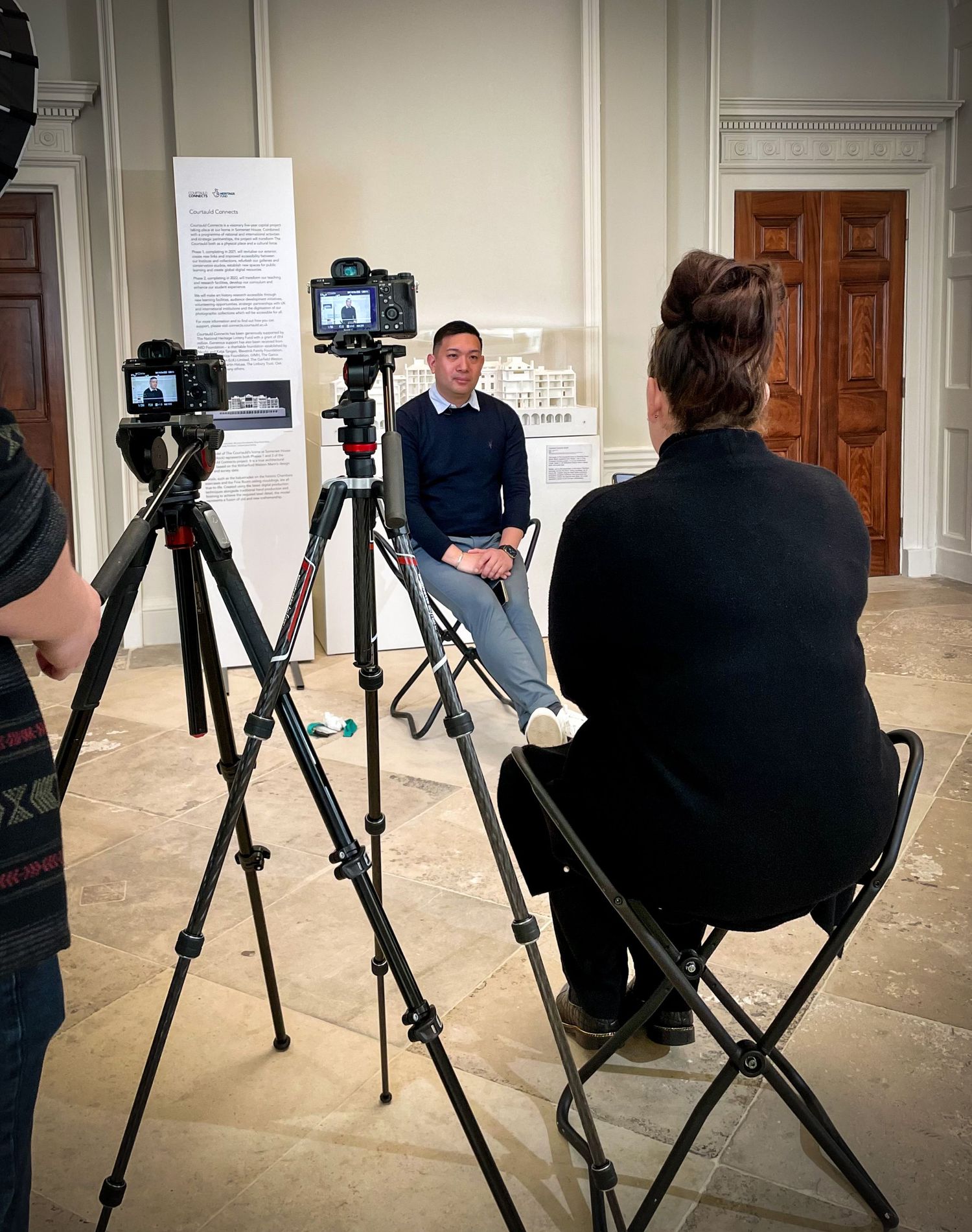 Photography setup with multiple tripods and camera equipment in an indoor gallery space.