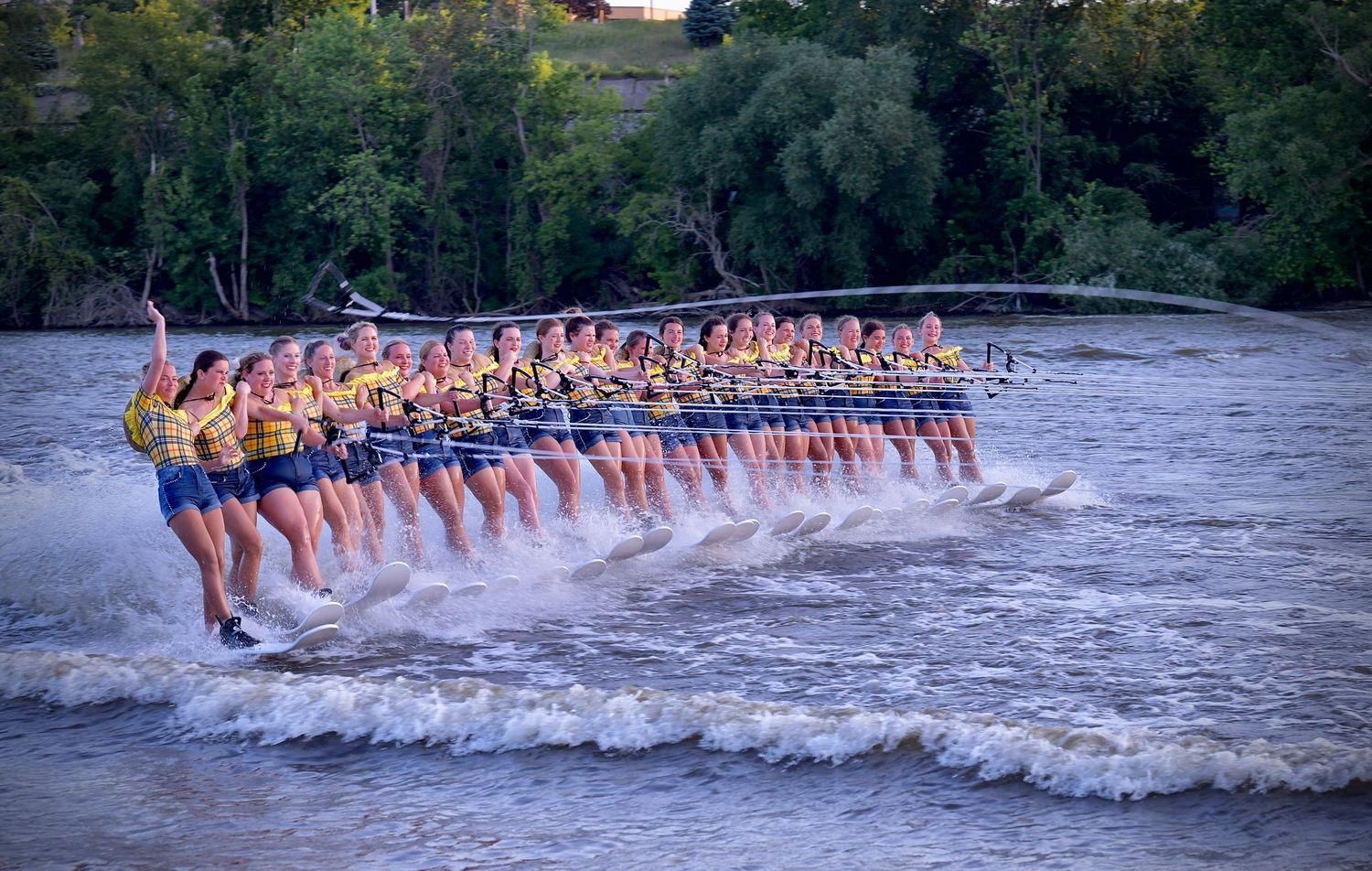 A large group of water skiers performing in formation on a lake, creating an impressive display of synchronized skiing.