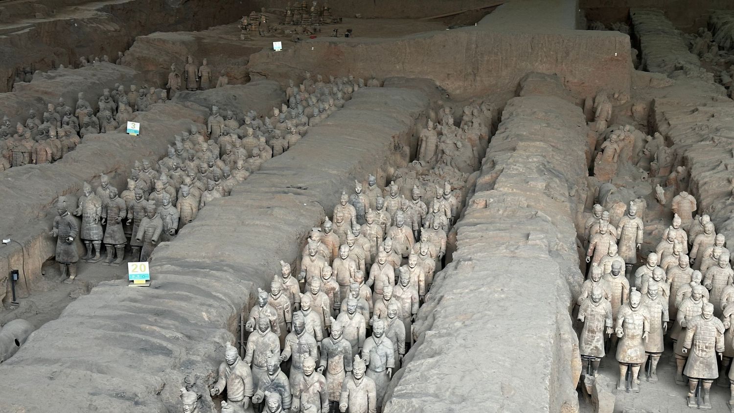 Rows of terracotta warriors standing in formation in an archaeological excavation site.