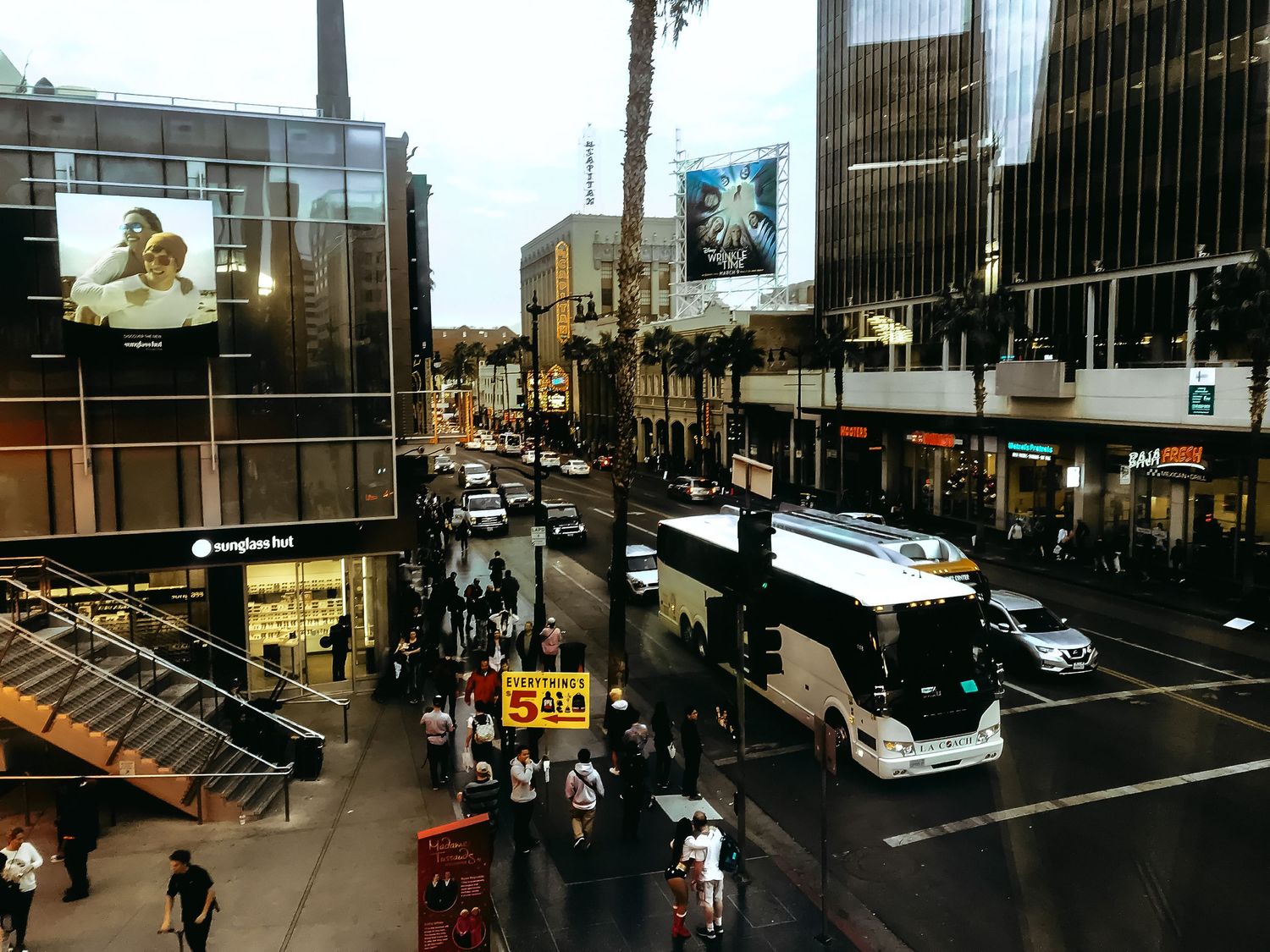 Aerial view of a busy Hollywood Boulevard with tour buses, pedestrians, and city buildings at dusk.