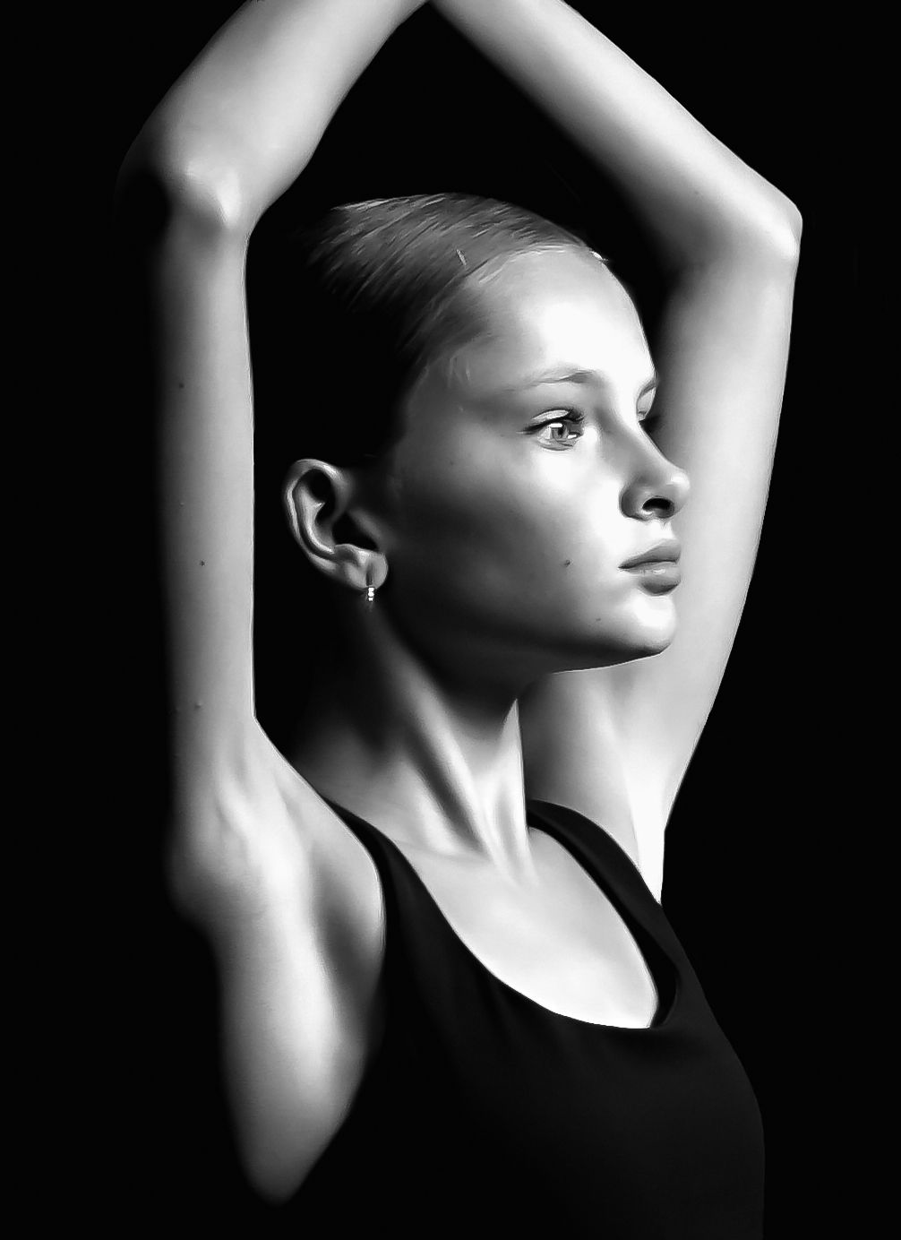 Black and white portrait of a young woman in a tank top with arms raised gracefully above her head.