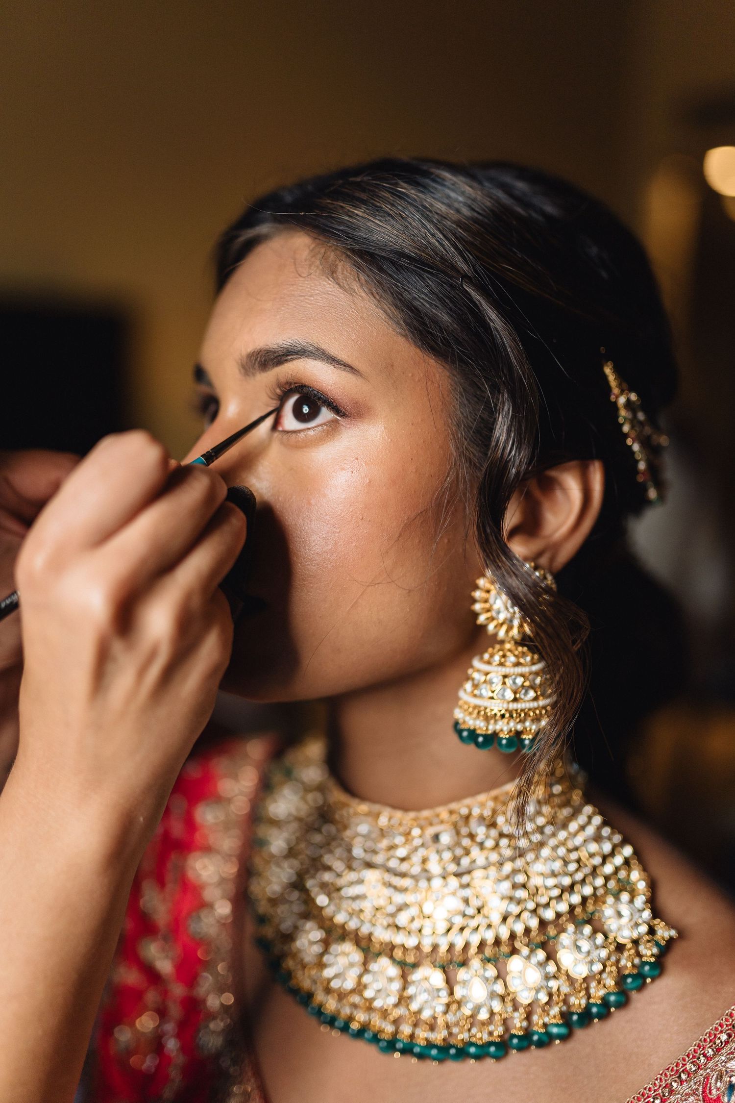 Close-up shots of intricate gold and turquoise Indian bridal jewelry being applied during wedding preparations.