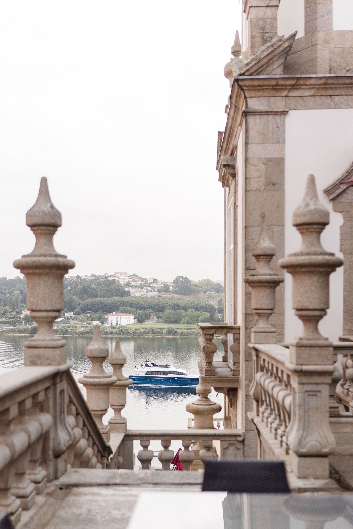 Stone balustrade overlooking a waterfront with a boat visible in the distance.