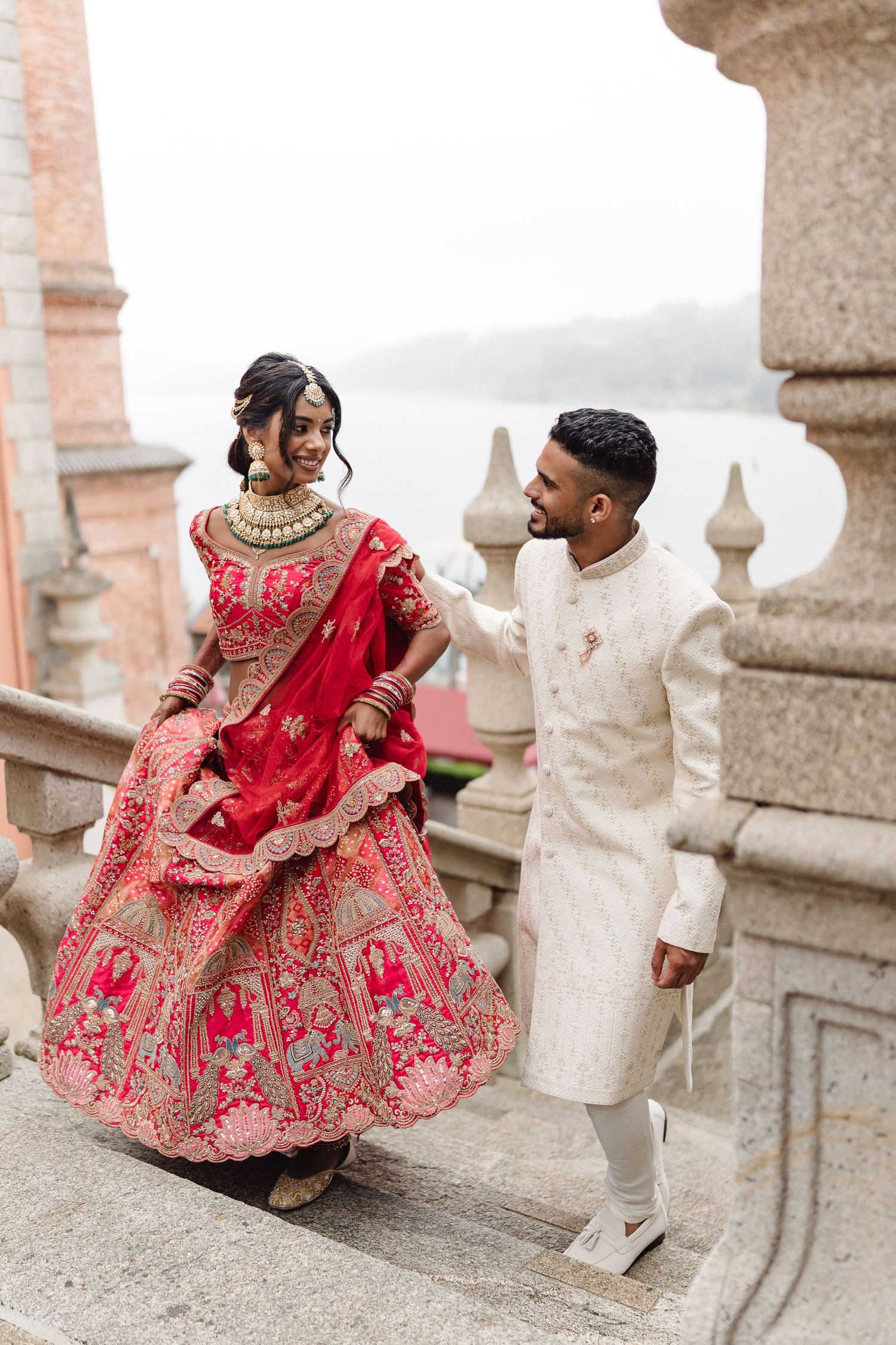 Romantic wedding photoshoot on stone balcony with traditional Indian attire.