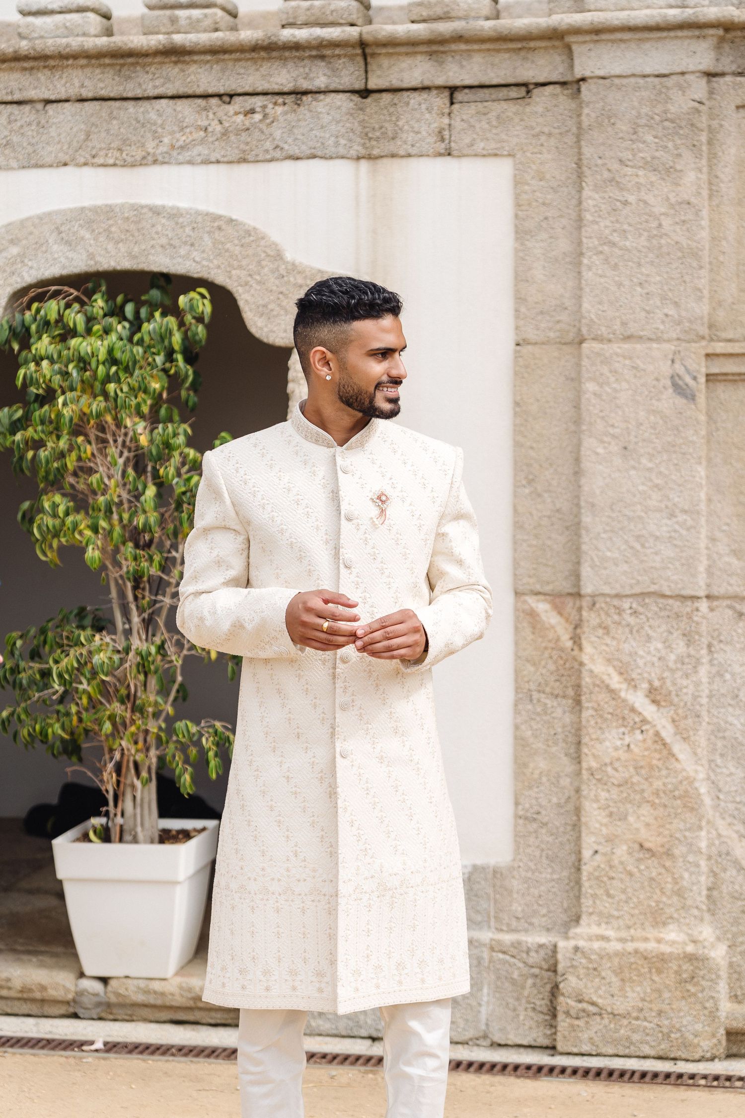 Elegant white traditional formal attire displayed against stone architecture.