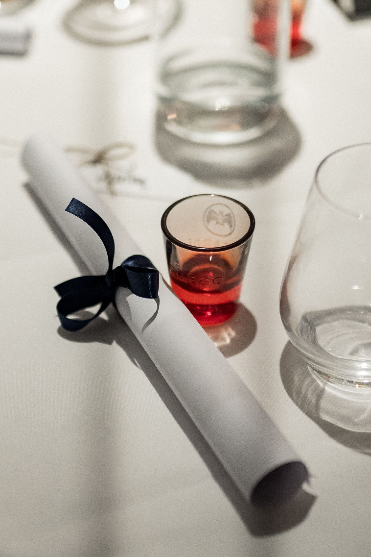 Decorative glass votive candle holders with black ribbon details on a white surface.