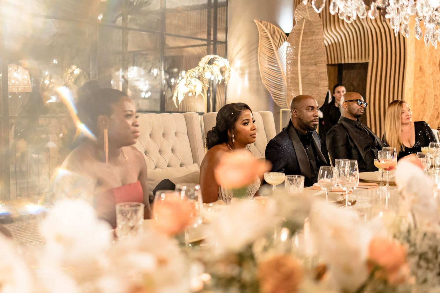Elegant wedding reception dinner setting with crystal chandeliers and soft ambient lighting.