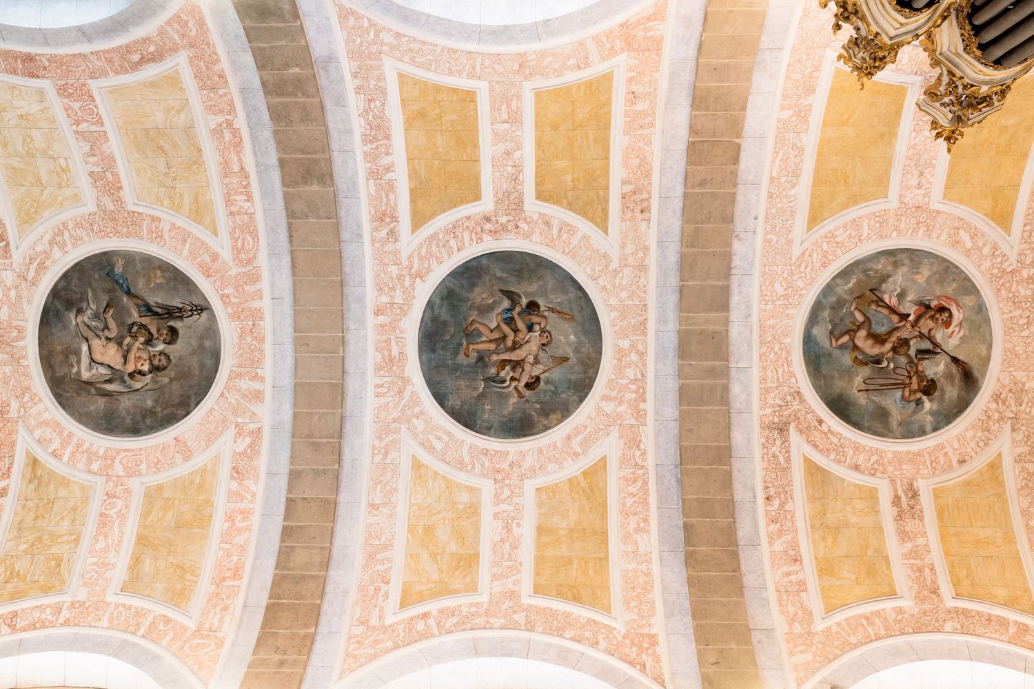 Ornate ceiling with classical painted decorations and architectural details in peach and gold tones.