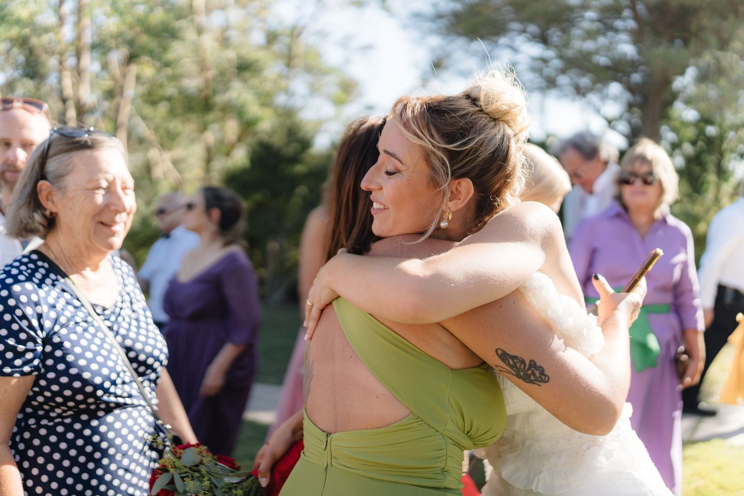 Wedding guests embracing and celebrating at an outdoor summer reception.